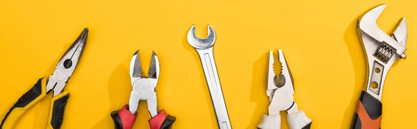 Top view of wrenches and pliers on yellow background, panoramic shot — Stock Photo