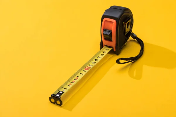 Cinta métrica industrial con sombra sobre fondo amarillo - foto de stock
