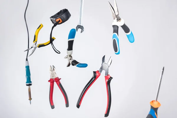 Set of tools with pliers and measuring tape levitating in air isolated on grey — Stock Photo