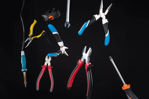 Ensemble d'outils avec tournevis et pinces lévitant dans l'air isolé sur noir — Photo de stock