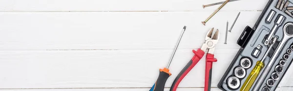 Top view of tool set with nails and wood screws on white wooden surface, panoramic shot — Stock Photo