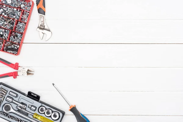 Vue du dessus des boîtes à outils avec clés et pinces sur fond blanc en bois — Photo de stock