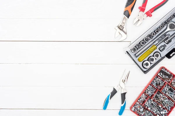 Top view of tool boxes with wrenches, bolts and nuts pliers on white wooden surface — Stock Photo