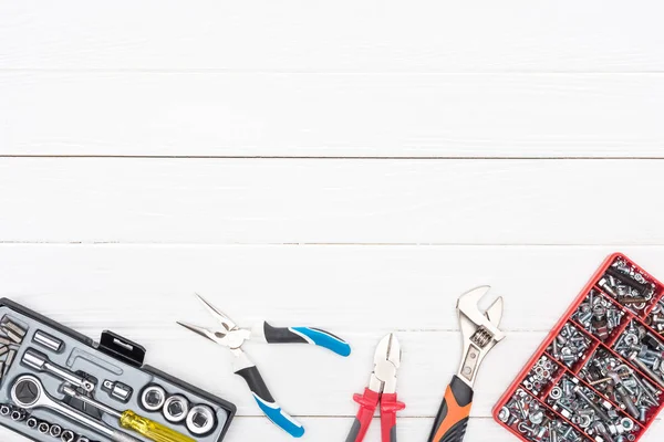 Vue du dessus des clés avec boîtes à outils et pinces sur fond de bois blanc — Photo de stock