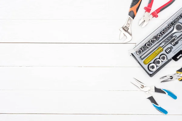 Top view of wrench in tool box and pliers on white wooden background — Stock Photo