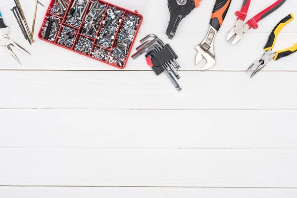 Vue du dessus de la boîte à outils avec pinces et clé sur fond blanc en bois — Photo de stock