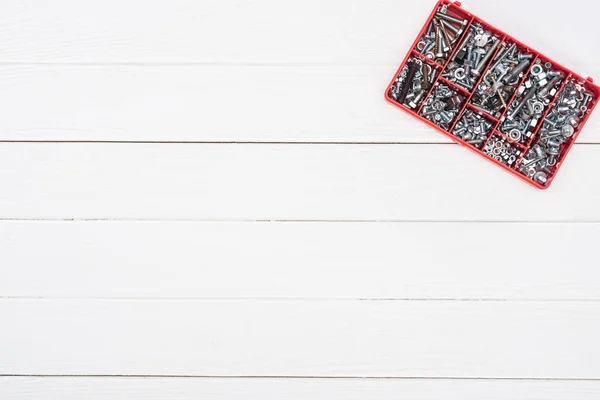 Top view of tool box with bolts and nuts on white wooden background — Stock Photo