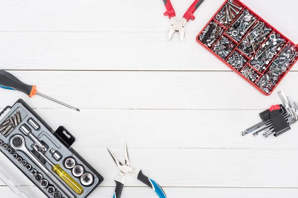 Vue du dessus des boîtes à outils avec pinces, clés hexagonales et clé sur fond blanc en bois — Photo de stock