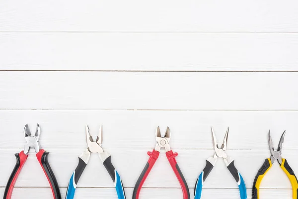 Top view of pliers on white wooden surface with copy space — Stock Photo