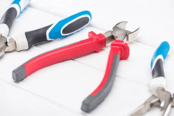 Selective focus of pliers on white wooden background — Stock Photo