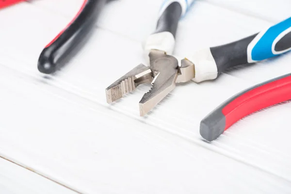 Close up view of pliers on white wooden surface — Stock Photo