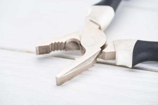 Close up view of pliers on white wooden background — Stock Photo