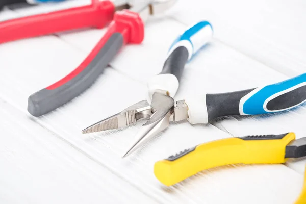 Close up view of metal pliers on white wooden background — Stock Photo