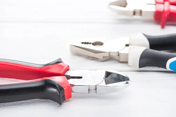 Close up view of metal pliers on white wooden surface — Stock Photo