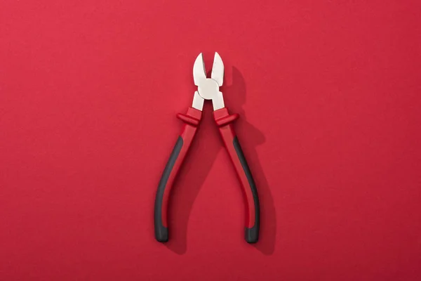Top view of pliers with shadow on red background — Stock Photo