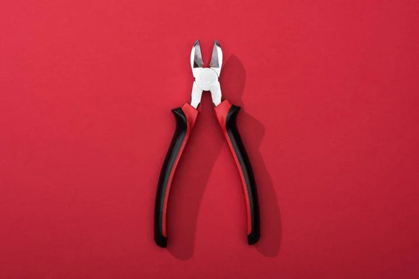 Top view of pliers with shadow on red surface — Stock Photo