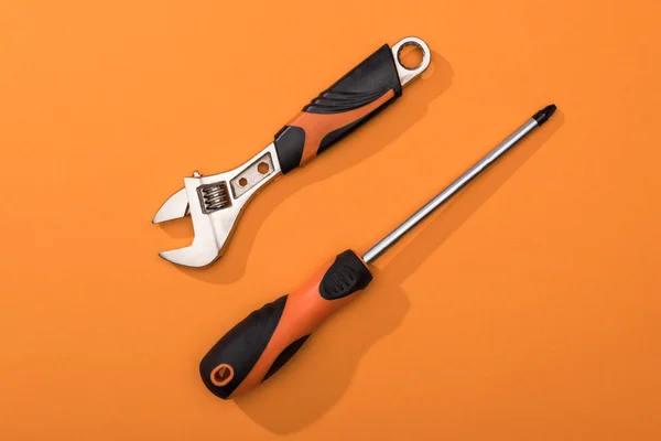 Top view of wrench and screwdriver on orange surface — Stock Photo
