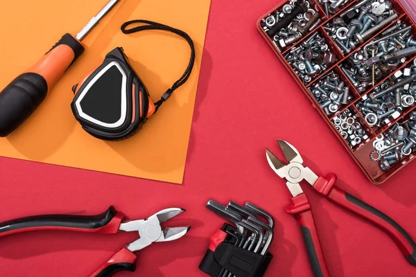 Vue du dessus de la boîte à outils avec pinces et clés hexagonales sur la surface orange et rouge — Photo de stock