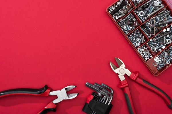 Ansicht des Werkzeugkastens mit Zange und Sechskantschlüssel auf roter Oberfläche — Stockfoto