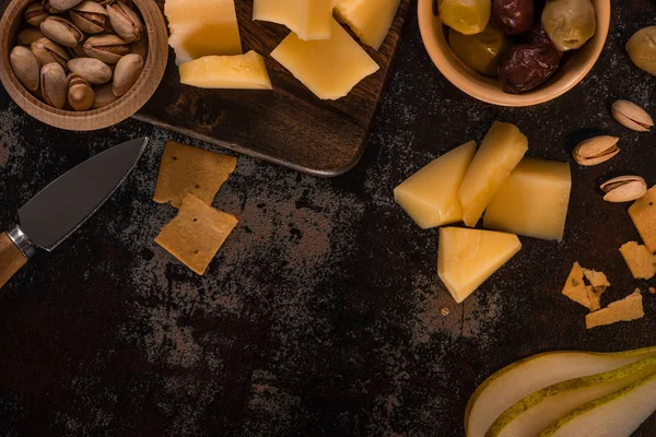 Vista superior de bandeja de queijo com pistache, pêra cortada, azeitonas e biscoitos na superfície intemperizada — Fotografia de Stock