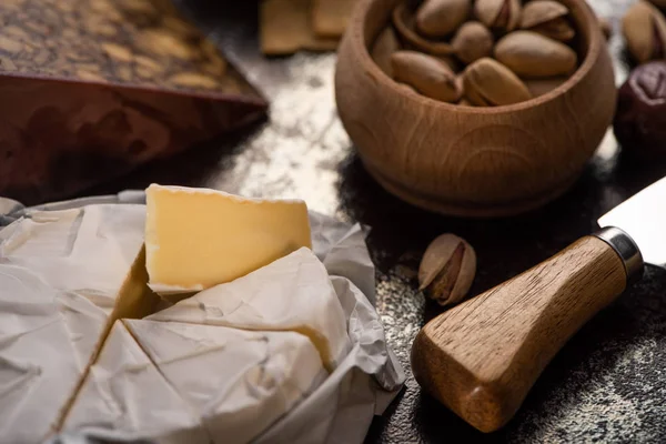 Vista de cerca de brie queso con cuchillo, pistachos - foto de stock