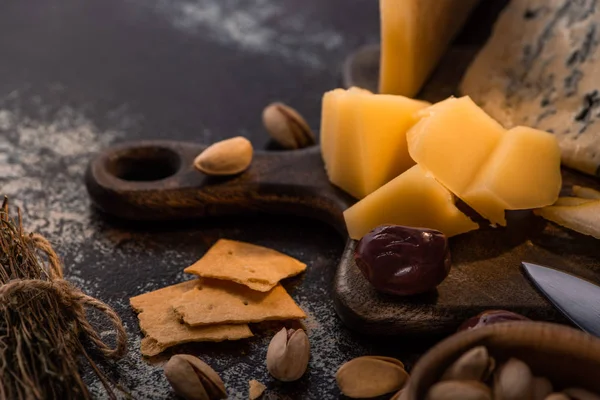 Vista de cerca de bandeja de queso con cuchillo, pistachos, aceitunas y galletas saladas - foto de stock