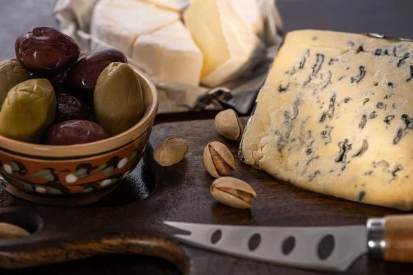 Selektiver Fokus von Dorblu und Brie-Käse mit Oliven und Pistazien in Messernähe — Stockfoto