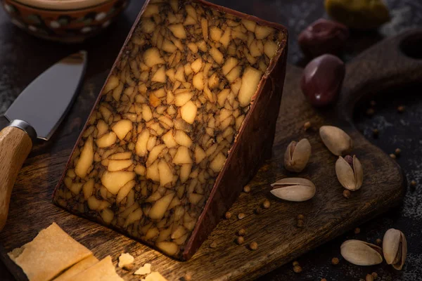 Piatto di formaggio con olive, cracker e pistacchi vicino al coltello — Foto stock