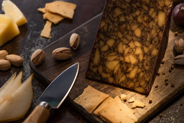 Cheese platter with pear slices, olives, crackers and pistachios near knife — Stock Photo