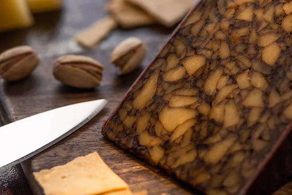 Vista de perto de prato de queijo com biscoitos e pistácios perto de faca — Fotografia de Stock