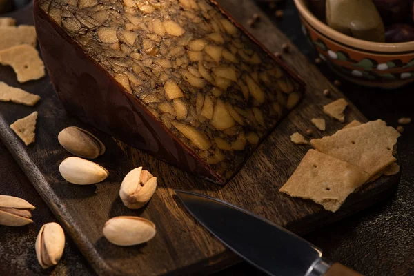 Piatto di formaggio con cracker e pistacchi vicino al coltello — Foto stock