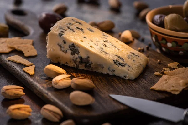 Selective focus of cheese platter with dorblu, olives, crackers and pistachios near knife — Stock Photo