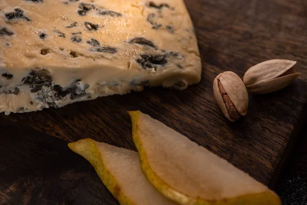 Vista de perto de prato de queijo com dorblu, pêra fatiada e pistache — Fotografia de Stock