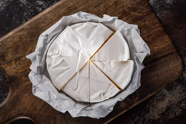 Vista superior del queso brie cortado sobre tabla de cortar de madera - foto de stock