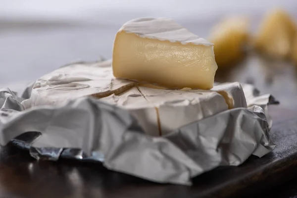 Close up view of cut brie cheese on wooden cutting board — Stock Photo