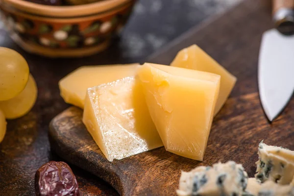 Close up view of cheese platter with olives, grapes near knife — Stock Photo