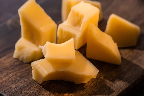 Nahaufnahme einer hölzernen Platte mit Grana Padano Käse auf verwitterter Oberfläche im Sonnenlicht — Stockfoto