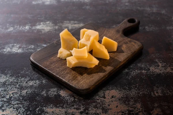 Wooden platter with Grana Padano cheese on weathered surface — Stock Photo