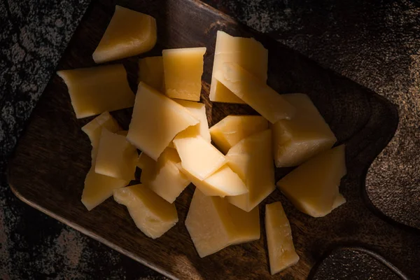 Vista superior de bandeja de madeira com queijo Grana Padano na superfície resistida à luz solar — Fotografia de Stock