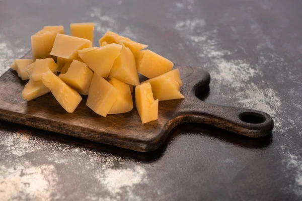 Wooden platter with Grana Padano cheese on weathered surface — Stock Photo
