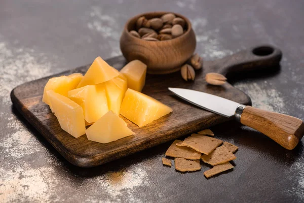 Bandeja de queso con Grana Padano, galletas y pistachos cerca del cuchillo - foto de stock