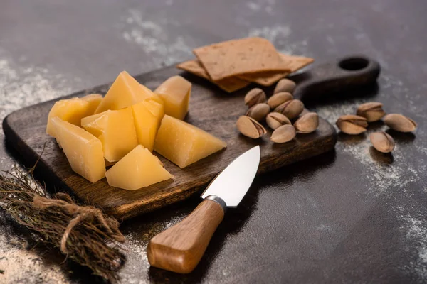 Bandeja de queso con Grana Padano, galletas y pistachos cerca del cuchillo - foto de stock