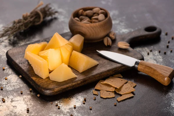 Cheese platter with Grana Padano, crackers and pistachios near knife — Stock Photo