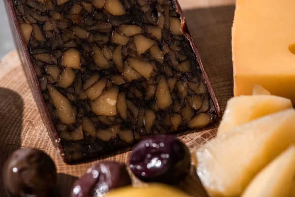 Enfoque selectivo del queso de nuez con aceitunas sobre fondo de madera - foto de stock