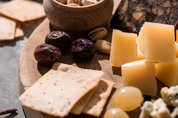 Foco seletivo de biscoitos, azeitonas, uvas, pistácios e pedaços de queijo em fundo de madeira — Fotografia de Stock