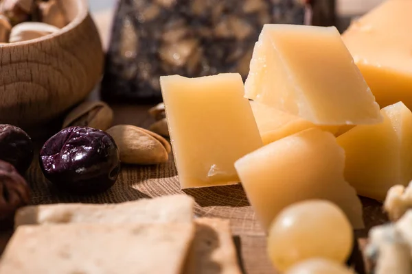 Foco seletivo de grana padano, bolachas, azeitonas e pistácios em fundo de madeira — Fotografia de Stock