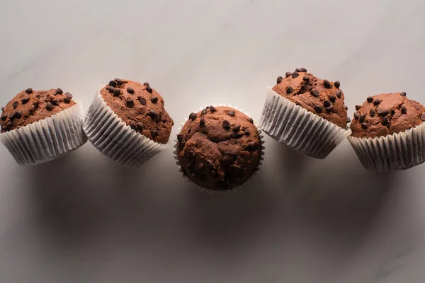 Вид сверху на свежие шоколадные кексы на мраморной поверхности — стоковое фото