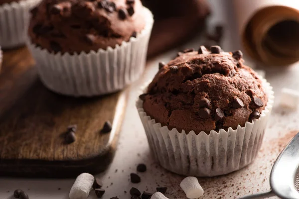 Vista de perto de muffins de chocolate fresco com marshmallow na placa de corte de madeira — Fotografia de Stock