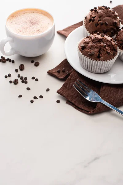 Frische Schokoladenmuffins auf weißem Teller neben Gabel und Kaffee — Stockfoto