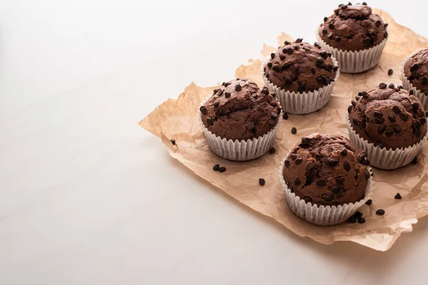 Fresh chocolate muffins on parchment paper — Stock Photo